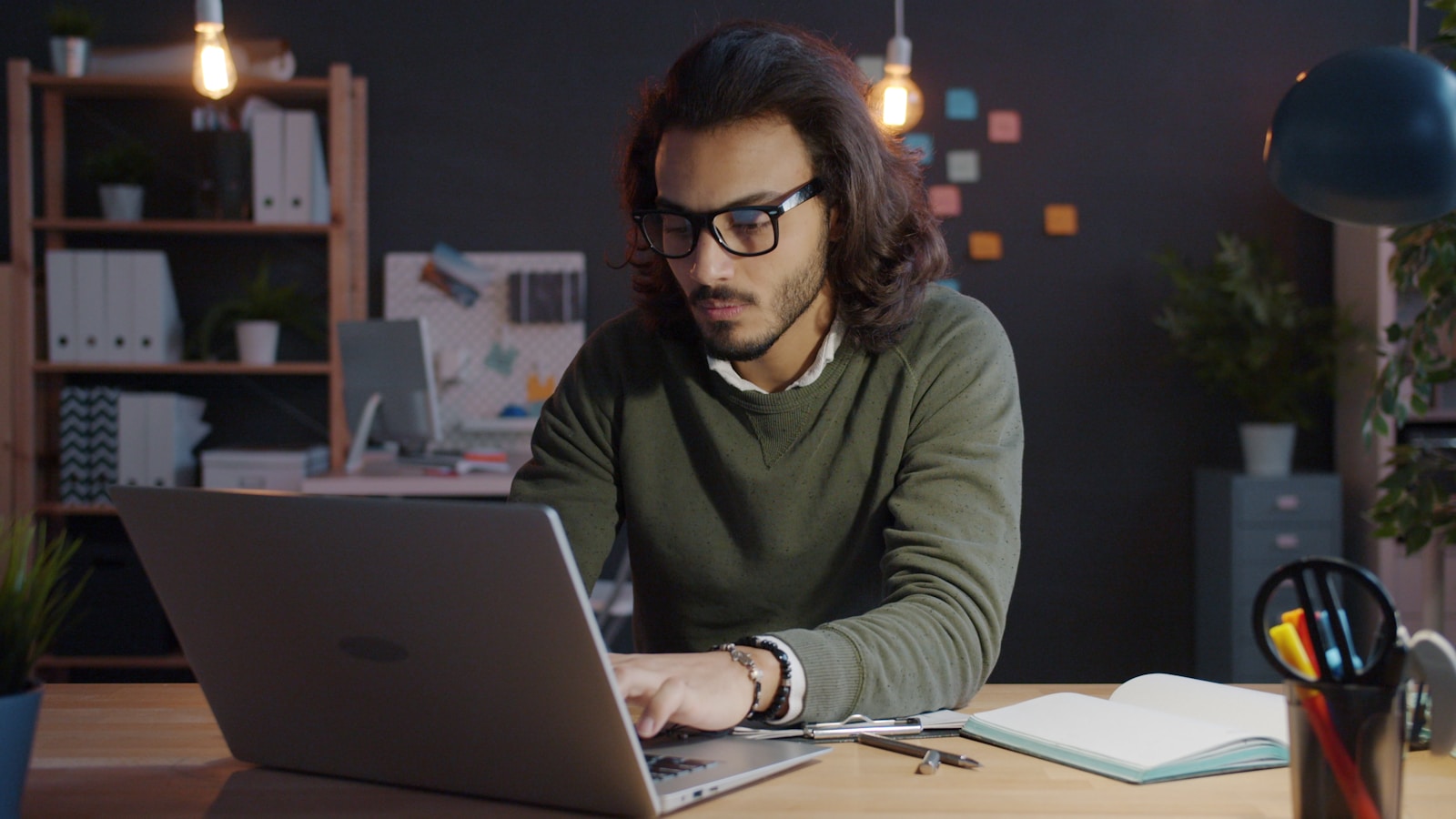 Man working on laptop in dimly lit office